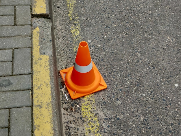 Un cono naranja con una raya blanca se encuentra al costado de una carretera.