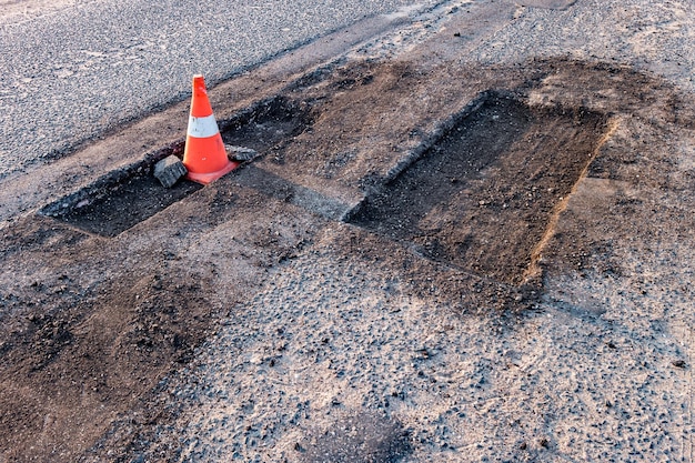 Cono de peligro de tráfico naranja blanco en la reparación de carreteras de asfalto