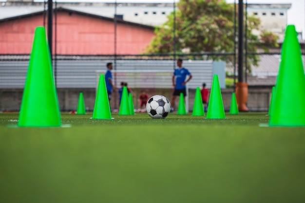 Foto cono de tácticas de balón de fútbol en campo de hierba con antecedentes de formación formación de niños en fútbol