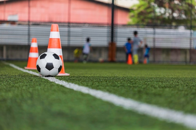 Cono de tácticas de balón de fútbol en campo de hierba con fondo de entrenamiento