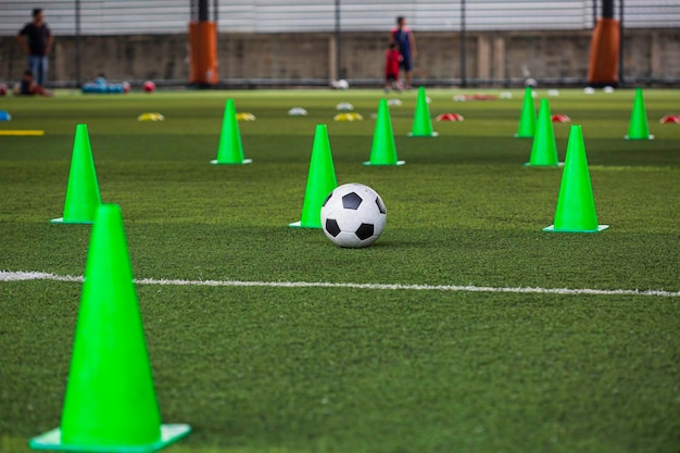 Cono de tácticas de pelota de fútbol en campo de hierba con antecedentes de entrenamiento