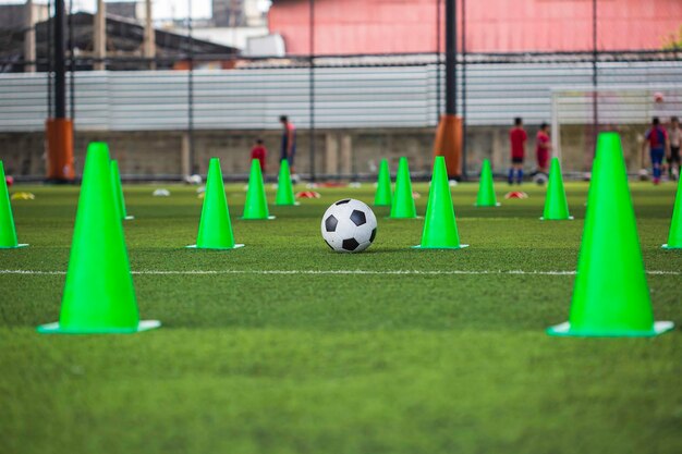 Cono de tácticas de pelota de fútbol en campo de hierba con antecedentes de entrenamiento