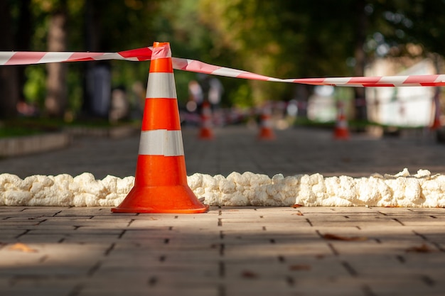 Cono de tráfico con cinta de precaución roja blanca.