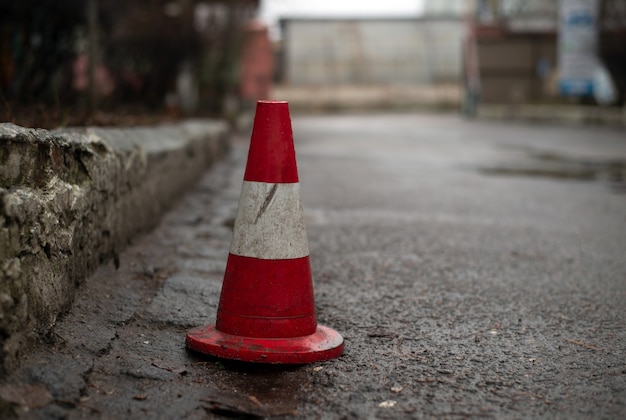 Un cono de tráfico parado en una calle a lo largo del bordillo de la acera para evitar que otras personas estacionen sus autos allí.