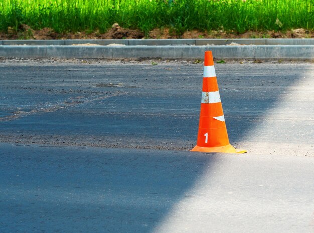 Cono de tráfico en la sombra en una carretera de nueva construcción