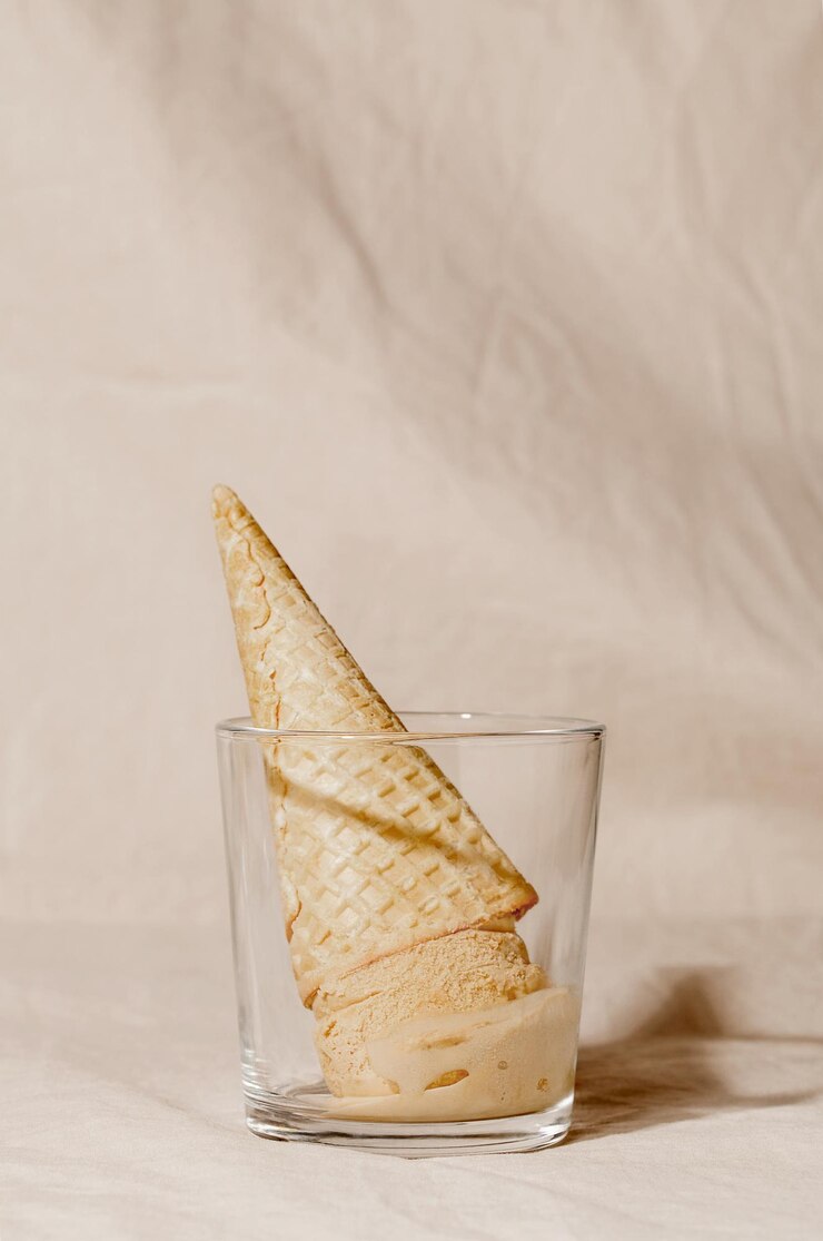 Cono de waffle de helado de maíz en vidrio sobre fondo pastel beige concepto creativo de verano