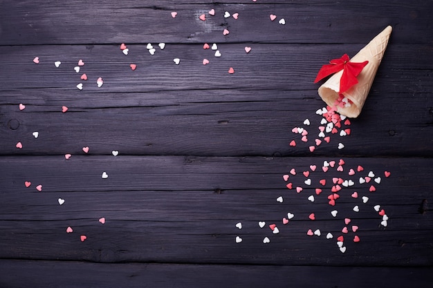 Cono de waffle y muchos corazones pequeños sobre fondo negro. Fondo de amor romántico para el día de San Valentín