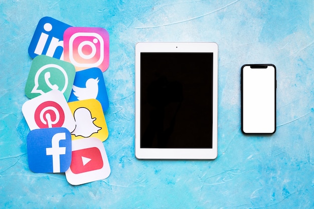Foto conocidas marcas de medios sociales impresas en papel dispuestas cerca de tableta digital y teléfono inteligente