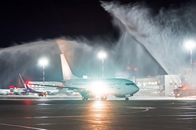 Conociendo un nuevo avión en un aeropuerto nocturno, la tradición de lavar rociando agua de los camiones de bomberos