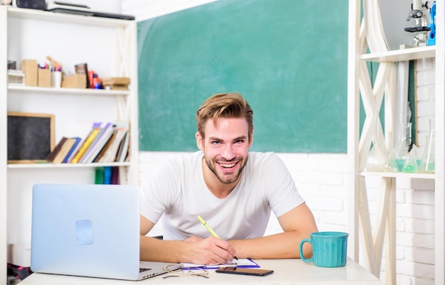 Conocimiento Experiencia hombre en el aula con taza de té concepto de educación moderna maestro de escuela universitaria usar computadora portátil y teléfono inteligente de regreso a la escuela Día de trabajo mañana hombre tomar nota y tomar café