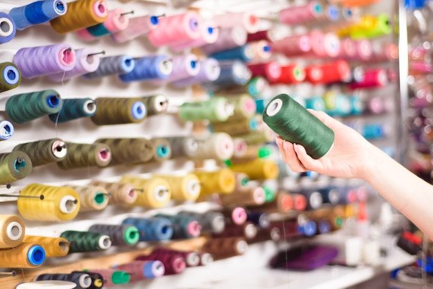 Conos de colores y carretes de hilo en un atelier. Sastrería, industria de la confección, concepto de taller de diseño.