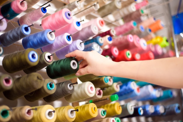 Conos de colores y carretes de hilo en un atelier. Sastrería, industria de la confección, concepto de taller de diseño.