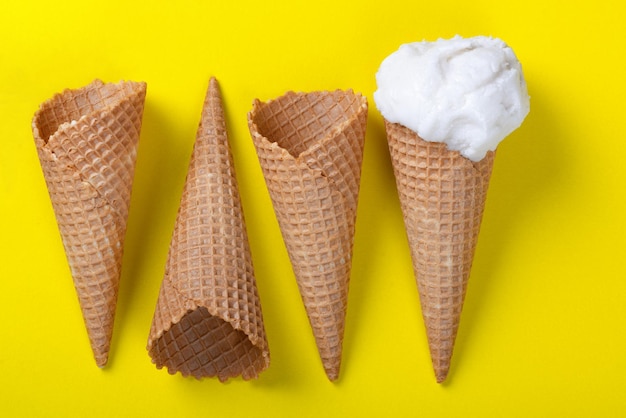Conos de gofres de helado y conos de helado sobre fondo amarillo plano