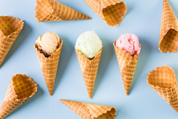 Conos de helado de galleta con bolas de helado sobre un fondo azul.