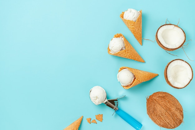 Conos de helado de galleta con cocos sobre fondo azul. Vista superior, espacio de copia.