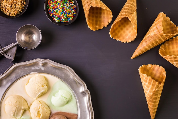 Conos de helado de galleta con plato de bolas de helado en un plato.