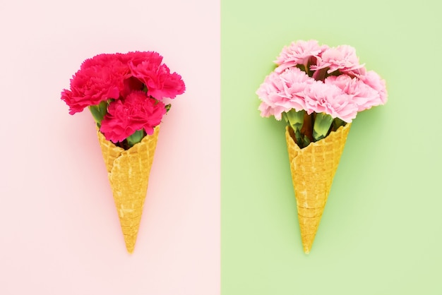 Conos de helado de gofre con flores de clavel rosa sobre fondo rosa verde