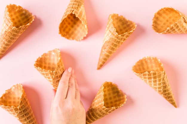 Conos de helado de gofres vacíos sobre un fondo rosa.