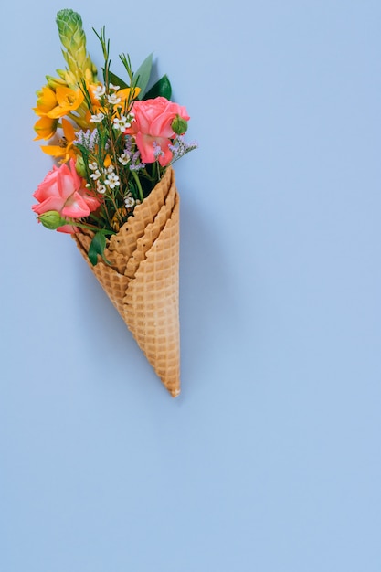 Conos de helado planos con colorido ramo en azul, espacio de copia