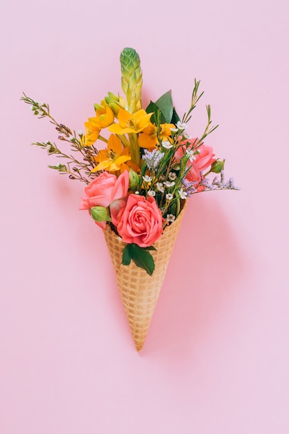 Foto conos de helado planos de la endecha con el ramo colorido en rosa, espacio de la copia