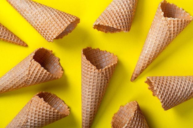 Conos de helado vacíos de gofres sobre fondo amarillo plano