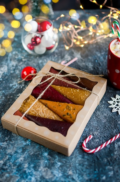 Conos de pastila de frutas en una caja de regalo y taza de cacao con malvaviscos en Navidad