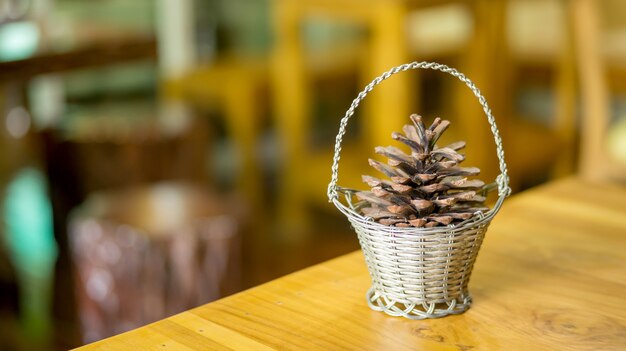 Conos de pino en una cesta en una mesa de madera