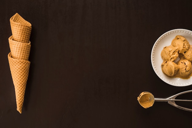 Foto conos de waffle cerca de bolas de helado en un plato y cuchara