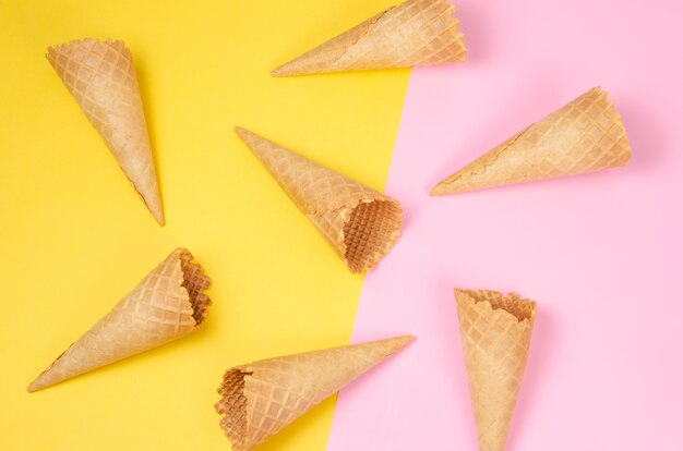 Foto conos de waffle de helado sobre fondo rosa claro y amarillo claro dulce como patrón