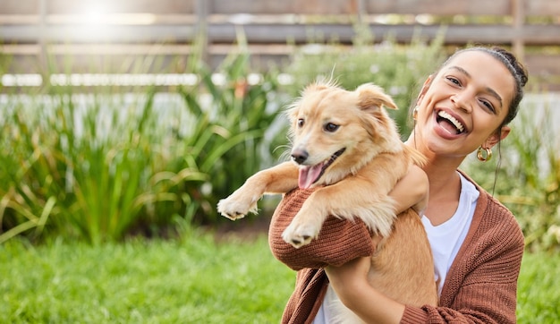 Conozca a mi nueva instructora de yoga Retrato de una mujer joven y atractiva sosteniendo juguetonamente a su perro en el jardín