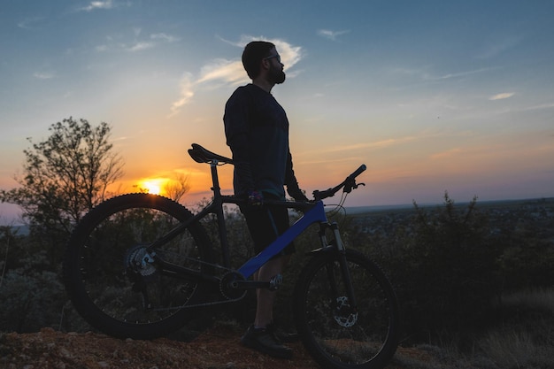 Conquistando os picos das montanhas por um ciclista de bermuda e malha em uma moderna bicicleta rígida de carbono com um garfo de suspensão a ar