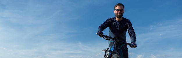 Conquistando picos de montanha por ciclista em shorts e camisa em uma moderna bicicleta hardtail de carbono com um garfo de suspensão a ar Linda vista da montanha