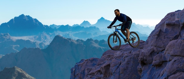 Conquistando los picos de las montañas por un ciclista en pantalones cortos y camiseta en una moderna bicicleta rígida de carbono con una horquilla de suspensión neumática Hermosa vista desde la montaña Vista panorámica para pancarta