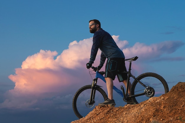 Conquistando los picos de las montañas por un ciclista en pantalones cortos y camiseta en una moderna bicicleta rígida de carbono con una horquilla de suspensión neumática Hermosa vista desde la montaña