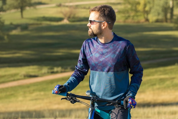 Conquistando los picos de las montañas por un ciclista en pantalones cortos y maillot en una bicicleta de carbono moderna
