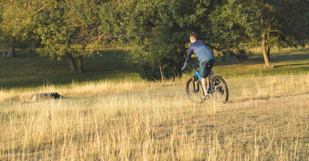 Conquistando los picos de las montañas por ciclista en pantalones cortos y maillot en una moderna bicicleta rígida de carbono con una horquilla de suspensión neumática