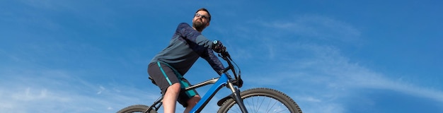 Conquistando los picos de las montañas por ciclista en pantalones cortos y maillot en una moderna bicicleta rígida de carbono con una horquilla de suspensión neumática