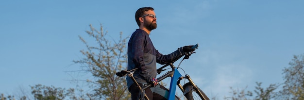 Conquistando los picos de las montañas por ciclista en pantalones cortos y maillot en una moderna bicicleta rígida de carbono con una horquilla de suspensión neumática