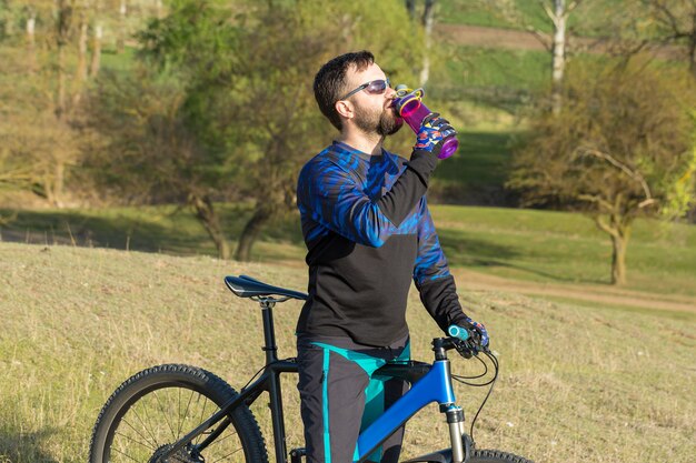 Conquistando los picos de las montañas por ciclista en pantalones cortos y maillot en una moderna bicicleta rígida de carbono