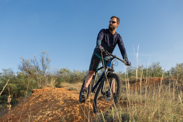 Conquistando los picos de las montañas por ciclista en pantalones cortos y maillot en una moderna bicicleta rígida de carbono