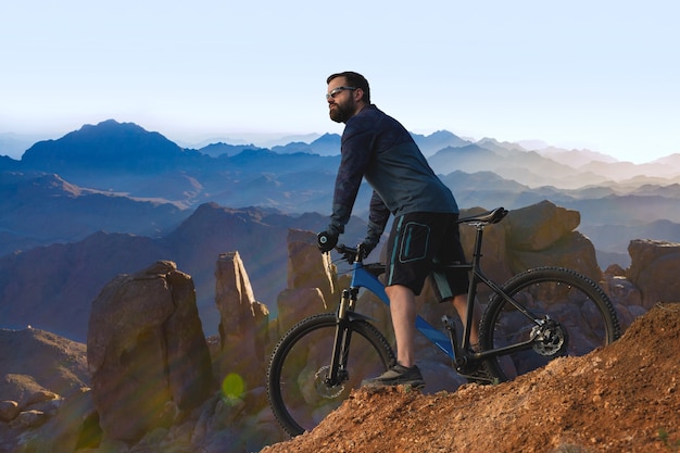 Foto conquistando los picos de las montañas por ciclista en pantalones cortos y maillot en una moderna bicicleta rígida de carbono