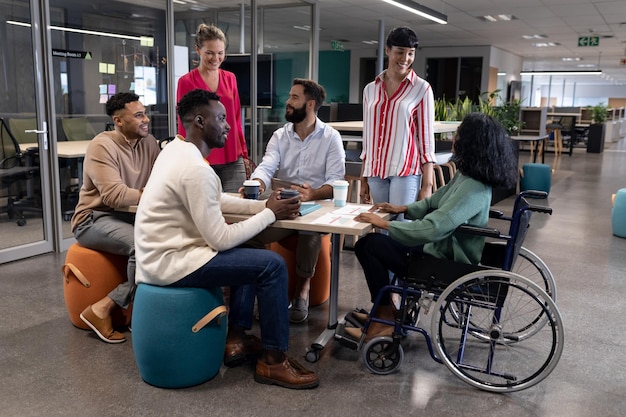 Conselheira afro-americana com deficiência discutindo com colegas birraciais em reunião no local de trabalho