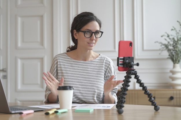 Conselheira de economista italiana confiante gravando fluxo de vídeo online usando smartphone