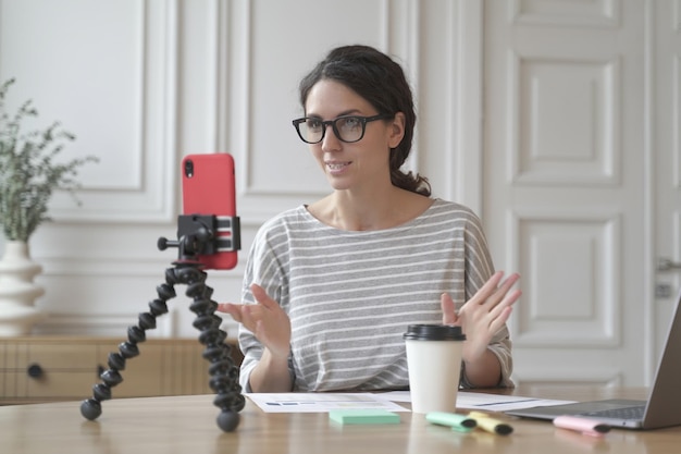 Conselheira de economista italiana confiante gravando fluxo de vídeo online usando smartphone