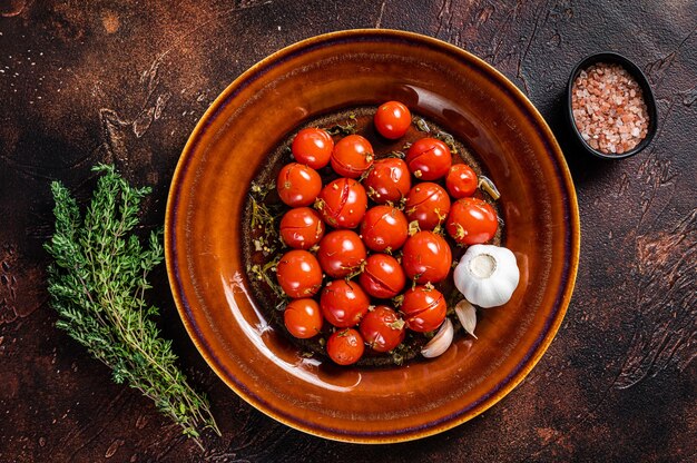 Conserva de tomates cherry marinados en un plato rústico con ajo y tomillo