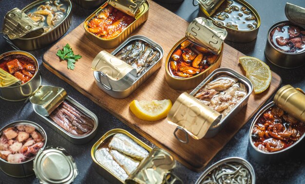 Conservar latas con diferentes productos del mar abierto sobre una mesa oscura con tablero de madera