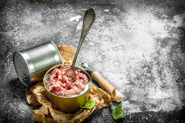 Conservas de carne en una lata sobre un fondo rústico