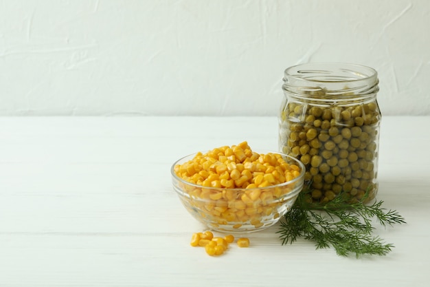 Conservas de guisantes y maíz en la mesa de madera blanca