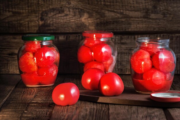 conservas de tomates rojos maduros en su propio jugo en tarros de cristal