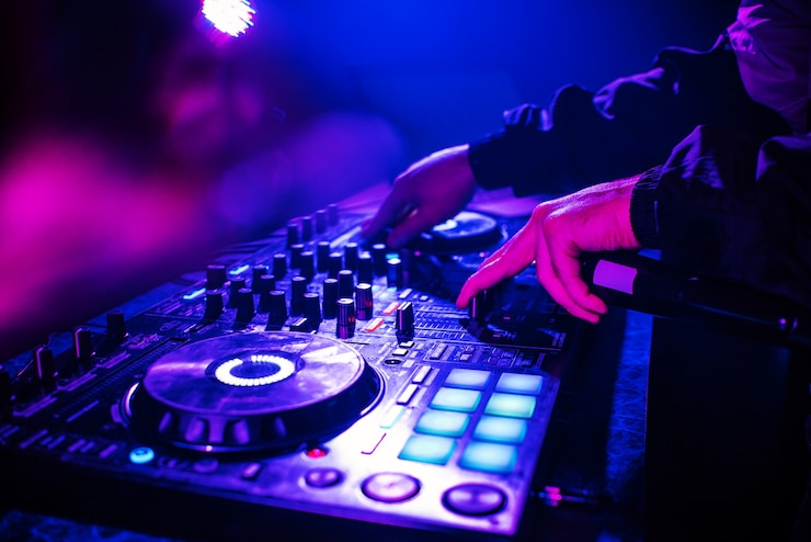 Foto consola de dj para mezclar música con las manos y con gente borrosa bailando en una fiesta de discoteca